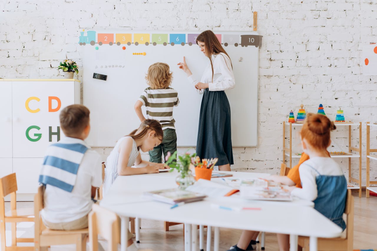 Teacher instructing children in a colorful classroom focused on learning activities.